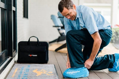 A Mr. Appliance washing machine repairman putting on his shoe covers before a service