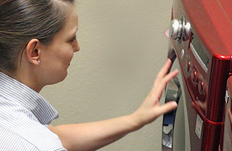 Mr. Appliance service professional assessing a red front-loading washer.