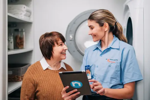 A smiling Mr. Appliance service professional helping a homeowner with a broken dryer.