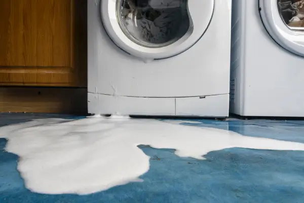 Soap bubbles leaking out of a broken washing machine.