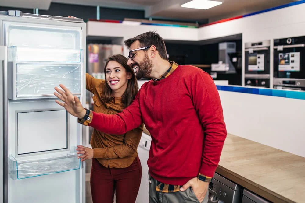 happy couple looking at new fridge