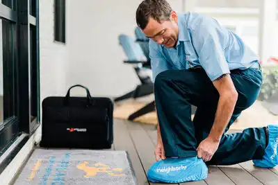 A Mr. Appliance fridge repair tech putting on shoe covers