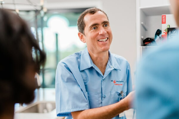 Mr. Appliance tech smiling at homeowners with the freezer door open