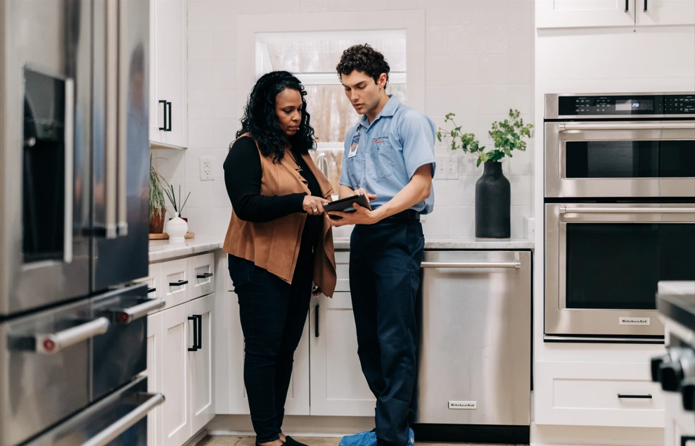 Mr. Appliance service professional consulting with homeowner about appliance repair.