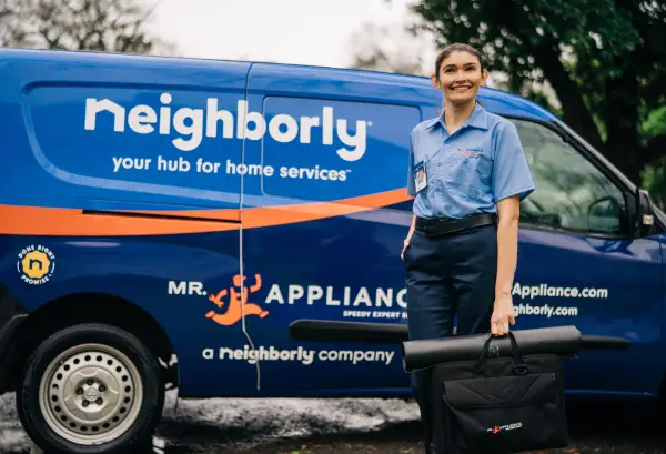 Mr. Appliance service professional standing in front of the blue Neighborly van