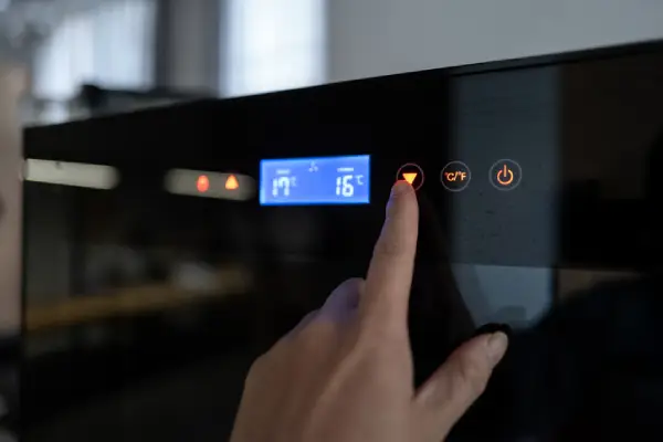 Hand adjusting the temperature on a dual-zone wine cooler.
